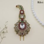 Gold-toned Kundan bridal hair accessory with pink and green stones and intricate traditional detailing