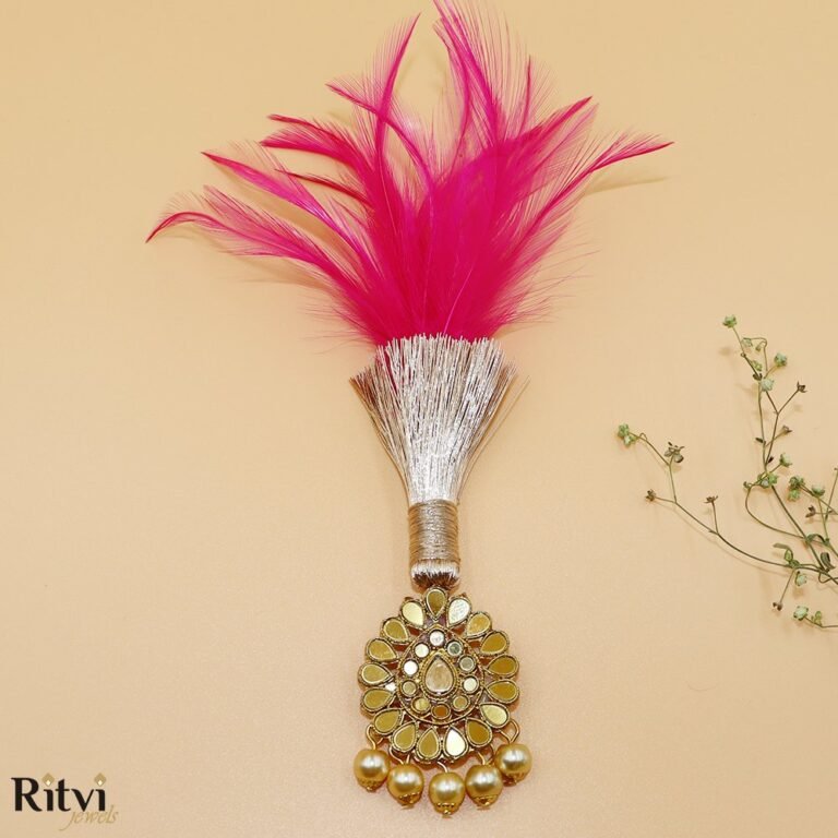 Pink feather bridal accessory with gold-toned embellishments, sparkling stones, and pearl drop detailing