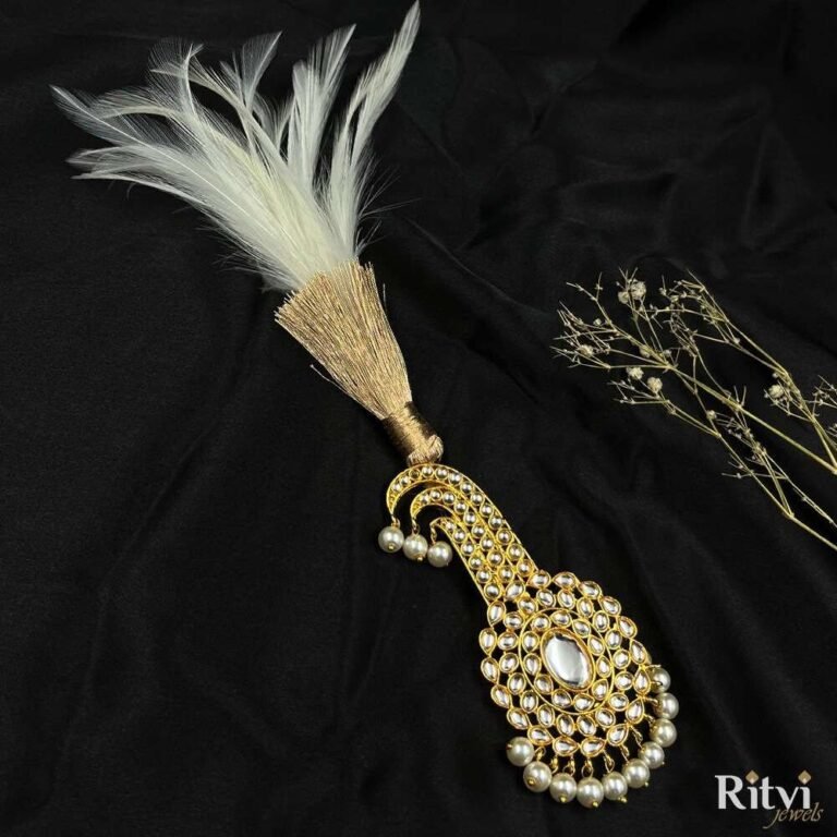White feather bridal accessory with gold-toned Kundan detailing, sparkling stones, and elegant pearl drop embellishments