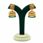 Gold-plated peacock jhumka earrings with kundan stones, antique finish, and green bead drops for bridal and festive ethnic wear.